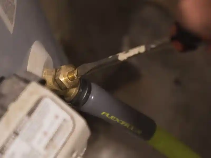 Plumber repairing a residential gas water heater in a Bonita Springs garage